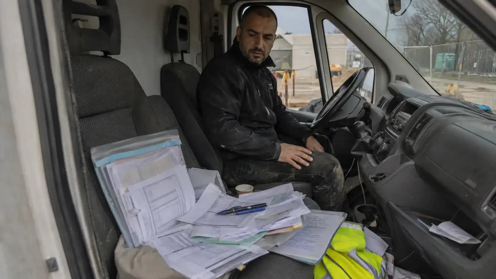 Pile de formulaires papier étalés sur le siège d'une camionnette de chantier